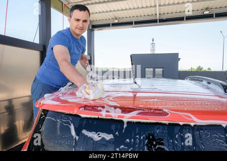 Manual car wash. A man with soapy water washes his car. Cleanliness concept Stock Photo