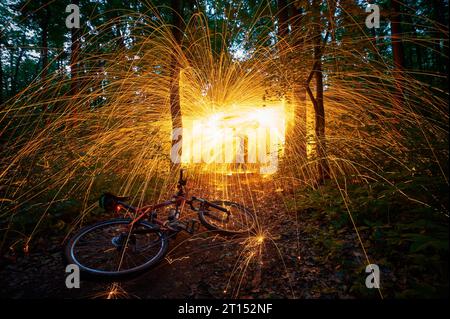 Burning steel wool spinned in the forest. Showers of glowing sparks from spinning steel wool at night. Stock Photo