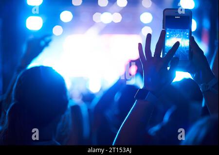 Crowd of audience with hands using camera phone to take pictures and videos at live concert, smartphone records live music festival. Unrecognizable pe Stock Photo