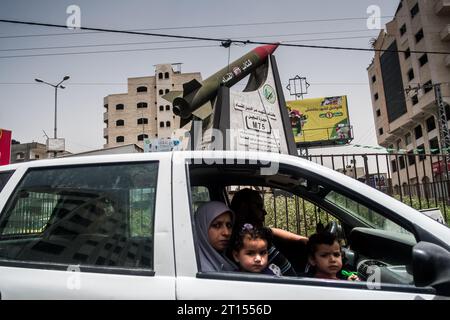 Michael Bunel / Le Pictorium -  Conflict in Gaza -  11/05/2018  -  Palestine / Gaza / Gaza  -  A family in a car drives past a traffic circle dominated by a statue of a missile in the colors of Palestine. On it is written that Al-qassam, the armed wing of Hamas will bomb Israel. May 10, 2018. Gaza. Palestine. Stock Photo