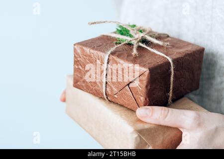Female hands holding gift handcrafted boxes thoughtfully wrapped in eco-friendly packaging. Sustainable and eco-conscious living concept Stock Photo