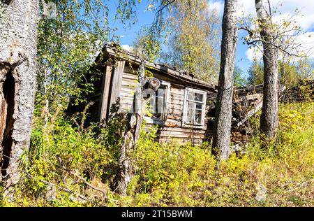 Rural abandoned broken wooden house in russian village in a summer sunny day. Countryside landscape with abandoned wooden house Stock Photo