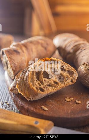Sliced wholegrain rustical baguette on the wooden table. Stock Photo