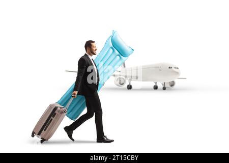 Businessman carrying a swim floating mattress and pullung a suitcase at the airport isolated on white background Stock Photo