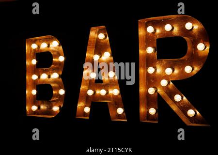 Bar signboard. Inscription from large metal letters decorated with glowing light bulbs. Stock Photo