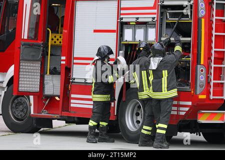 group of firefighters in action with the fire truck during the emergency with uniform and protective helmet Stock Photo