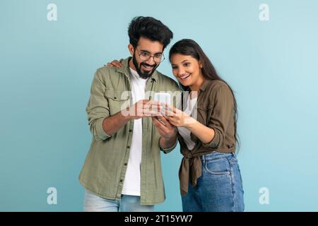 Amazed young indian couple shopping online, using smartphone Stock Photo