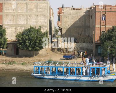 Egyptian transport: a blue & white water taxi picks up passengers from a small town on the east banks of the River Nile in Upper Egypt. Stock Photo
