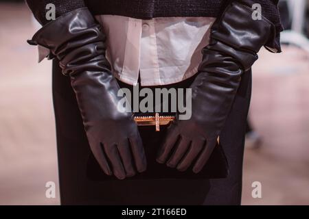 Fashion details of a classy black skirt, leather gloves and classic velvet clutch. Fashion model posing on backstage Stock Photo