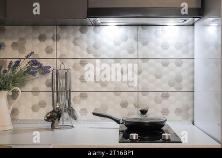 Frying pan on electric induction cooker in modern kitchen Stock Photo