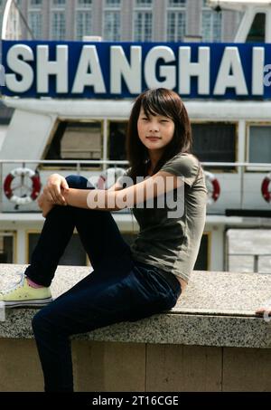 Chinese woman posing as a tour boat passes Stock Photo