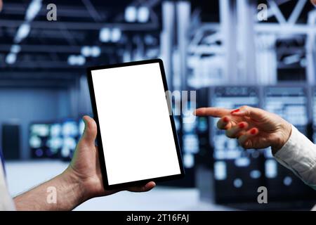 Elderly programmers in high tech workspace using mock up tablet to set up configuration management tools that enable automatic failover, preventing server cabinets system crash, close up Stock Photo