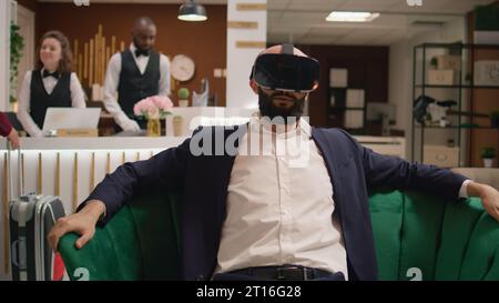 Middle eastern manager using vr glasses to create project simulation and ensure succes, working with virtual reality gadget. Entrepreneur projecting plan on headset, travelling for work. Stock Photo