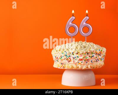 Candle number 66 - Vanilla cake in orange background Stock Photo