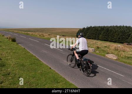 Dartmoor, Devon, Englaand, UK. 04.09.2023.  Man cycling on  an empty road  in Dartmoor national park in Devon, UK Stock Photo