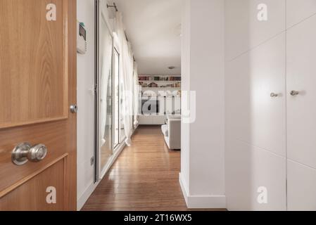 Hall of an apartment with a white built-in wardrobe and direct access to a living room Stock Photo