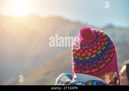 Back view of young traveler in hat standing over mountain peaks. Autumn traveling scene, wanderlust concept Stock Photo