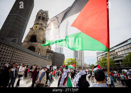 Berlin, Germany. 24th May, 2021. Participants in a rally have gathered with a Palestinian flag on Breitscheidplatz in front of the Kaiser Wilhelm Memorial Church. Following the attack by the Islamist Hamas on Israel with many hundreds of deaths, German Chancellor Olaf Scholz announced a ban on the organization's activities in Germany. In addition, the Palestinian network Samidoun is to be banned, as Scholz said in his government statement in the Bundestag on Thursday. Credit: Christoph Soeder/dpa/Alamy Live News Stock Photo