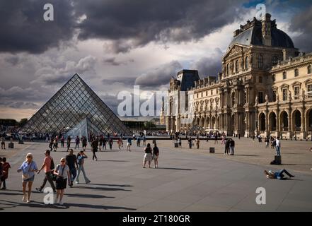 Tourists in Napoleon Courtyard next to the glass Louvre Pyramid and Louvre Museum, Paris, France. Stock Photo