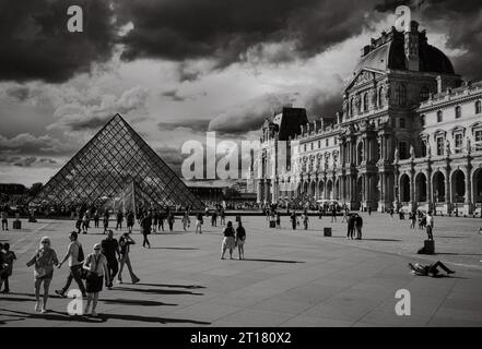 Tourists in Napoleon Courtyard next to the glass Louvre Pyramid and Louvre Museum, Paris, France. Stock Photo