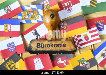 FOTOMONTAGE, Alter Stempel mit der Aufschrift Bürokratie auf den Fahnen der deutschen Bundesländern Stock Photo