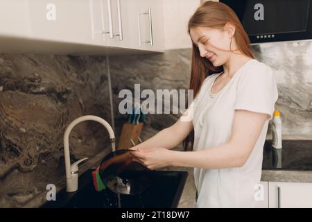 A housewife woman washes dishes in the kitchen in the sink. Stock Photo