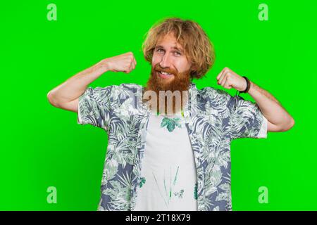 I am strong and independent. Young bearded man showing biceps and looking confident, feeling power strength to fight for rights, energy to gain success win. Guy isolated on green chroma key background Stock Photo