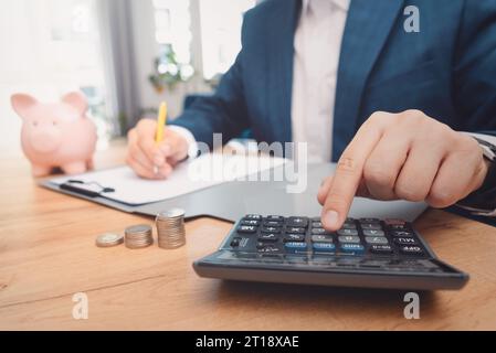 Man planning home budget and using calculator. Financial data analyzing counting on wood desk Stock Photo