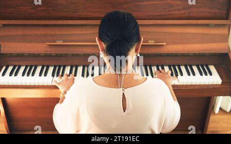 Musician, piano and person playing music in home living room for artistic musical and creativity talent learning. Back view, lounge and artist Stock Photo