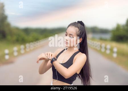 Female jogger Checking her Heart Rate on a smart watch, Thailand Stock Photo