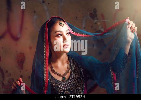 Portrait of young Indian Woman in traditional sari and veil with light on face Stock Photo
