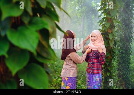 Smiling woman in a forest adjusting a friend's headscarf Stock Photo