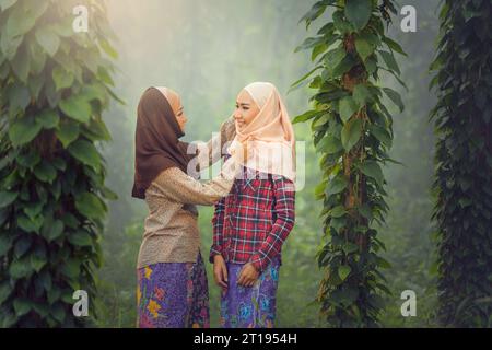 Smiling woman in a forest adjusting a friend's headscarf Stock Photo