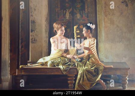 Two Asian women in traditional Thai clothing with a Thai Saw Duang stringed instrument, Thailand Stock Photo