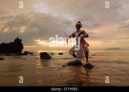 Masked khon dancer performing on beach at sunset, Thailand Stock Photo