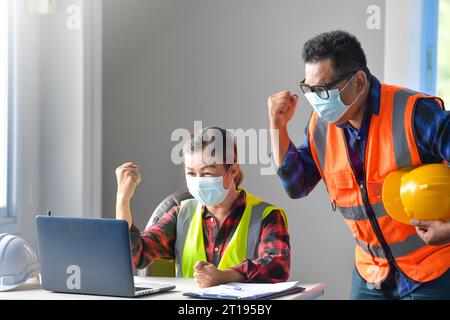 Two excited building inspectors in an office on a video call punching the air Stock Photo