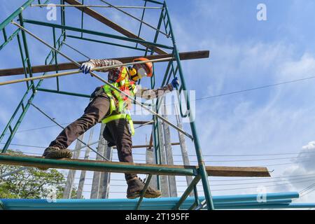 Low angle view of a Construction worker in a face mask standing on scaffolding, Thailand Stock Photo