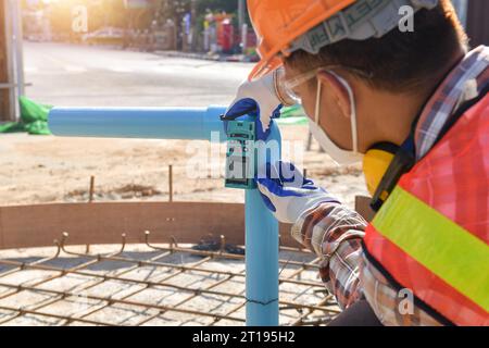 Construction worker using a  Laser measuring tool on a construction site, Thailand Stock Photo