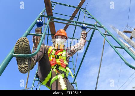 Low angle view of a Construction worker in a face mask standing on scaffolding, Thailand Stock Photo