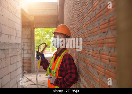 Construction worker standing on a building site holding a hook, Thailand Stock Photo