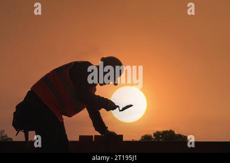 Silhouette of a bricklayer working on a construction site, Thailand Stock Photo