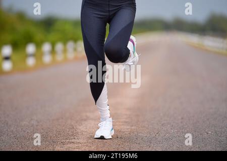 Close-up low angle view of a woman running down the middle of the road, Thailand Stock Photo