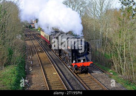British Railways Standard Class 7MT Pacific No. 70000 Britannia is seen passing Brockenhurst in the New Forest with it's support coach. Stock Photo