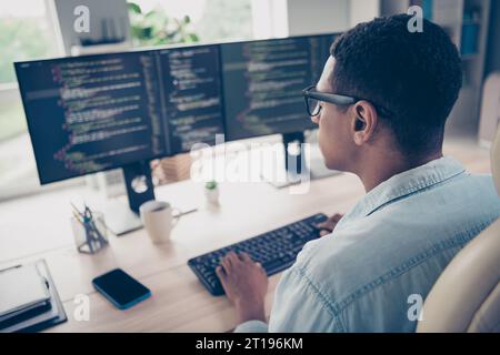 Side profile photo of serious man hardware expert sitting chair keyboard writing open space program system watch monitors in office Stock Photo