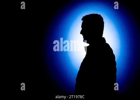 Silhouette of a young man against a blue background Stock Photo