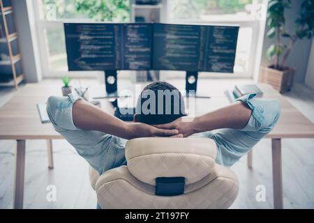 Rear photo of server operator successful guy it developer relaxing he done project hands head sitting armchair reviewing code on monitors Stock Photo