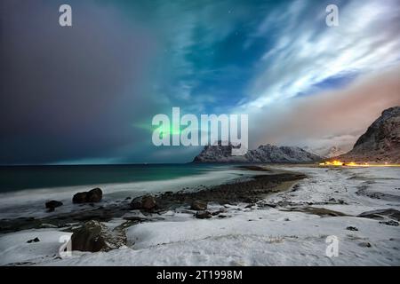 Northern lights over coastal snow covered beach in winter, Lofoten, Nordland, Norway Stock Photo
