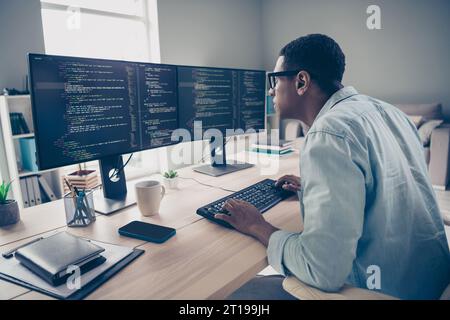 Side photo of focused concentrated serious programmer guy researching code mistakes errors debug fixing looking for solution in office Stock Photo