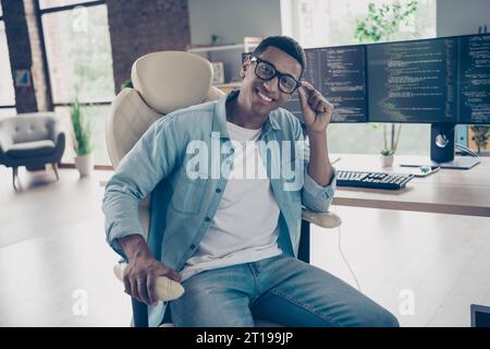 Portrait of cheerful skilled glad man junior dev ops engineer programmer in big company looking camera sitting armchair indoors office Stock Photo