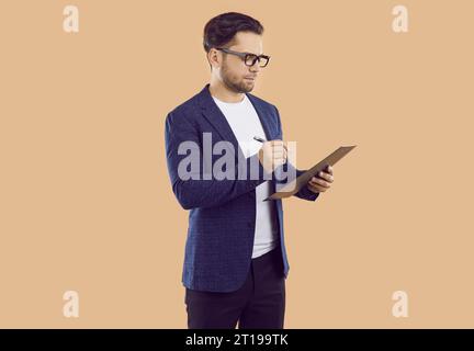 Business man or sales manager in suit and glasses writing something on clipboard Stock Photo